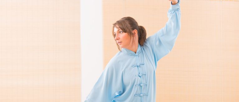 Frau im Karateanzug macht eine Qigong Übung